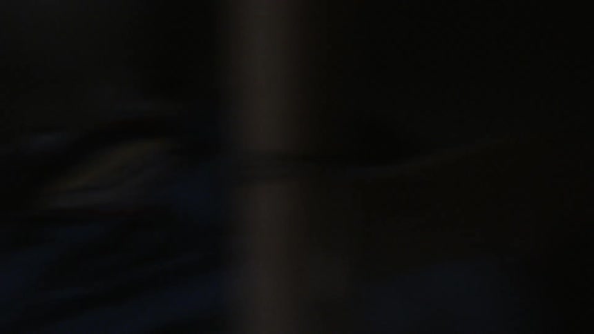 Woman walks into a dark bedroom looking at an empty bed