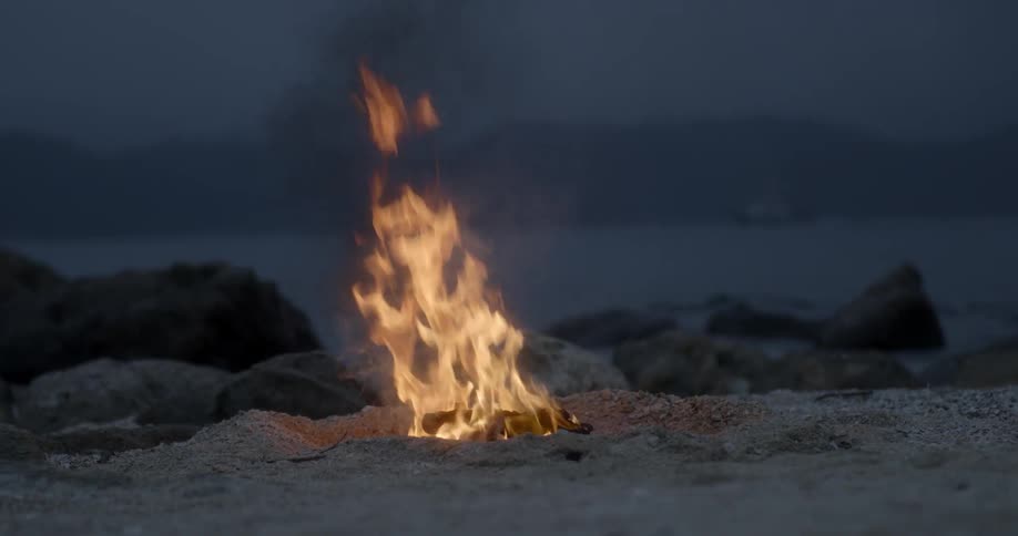 A fire is going on the beach at dusk