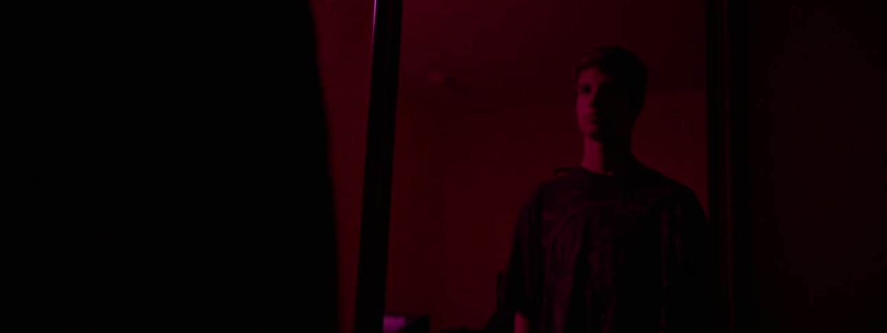 A green light flashes on a man staring into a mirror
