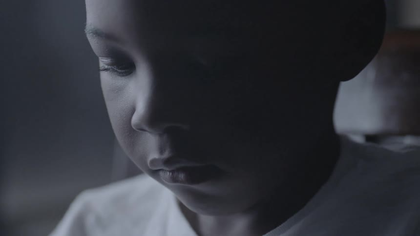 A young child is looking down at something offscreen