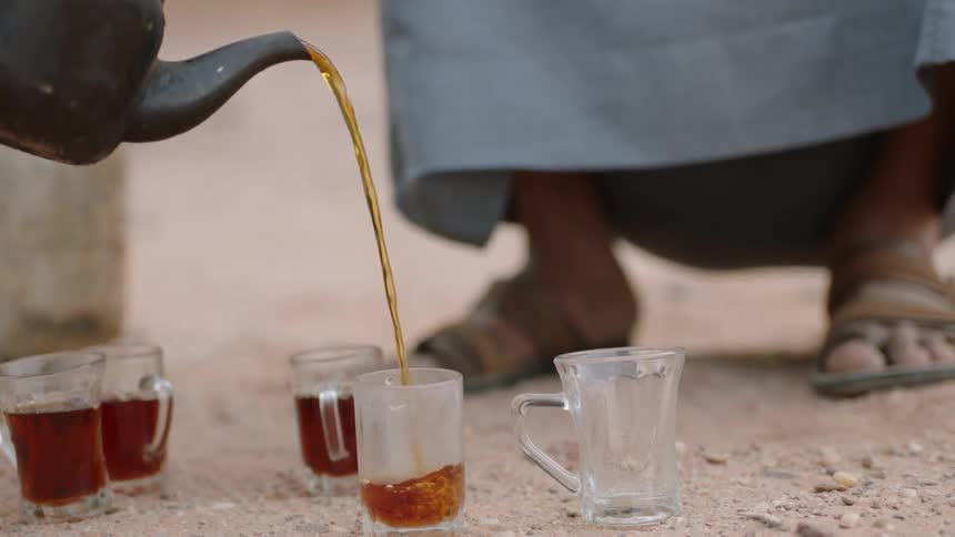 Tea is poured into glass cups on the ground
