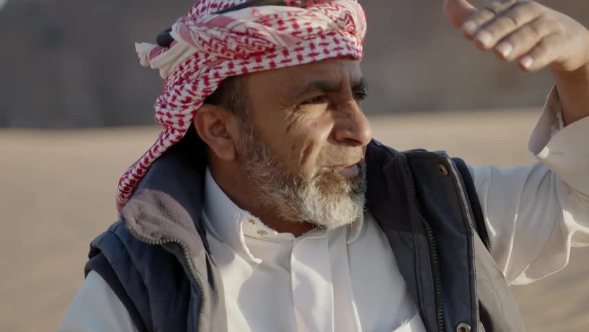 An arab man is shielding his eyes from the sun
