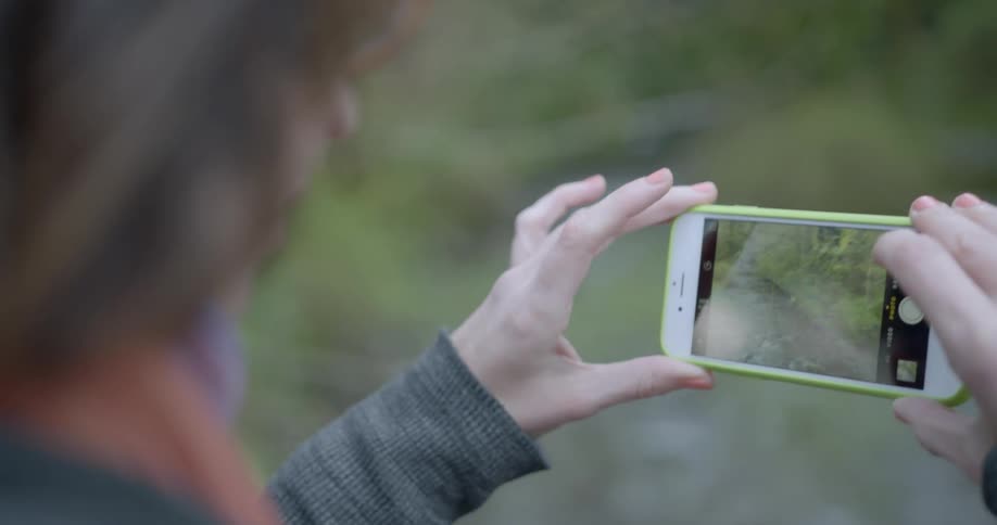 A woman wearing glasses takes a picture with an iphone