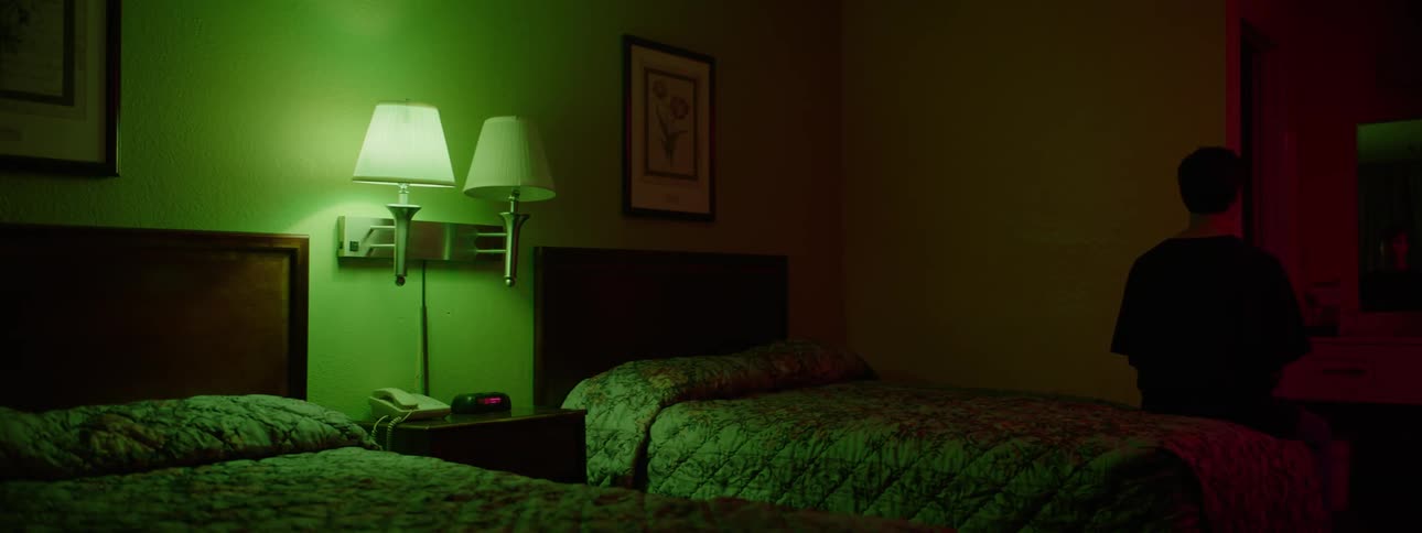 A motel room with two beds and one lamp on