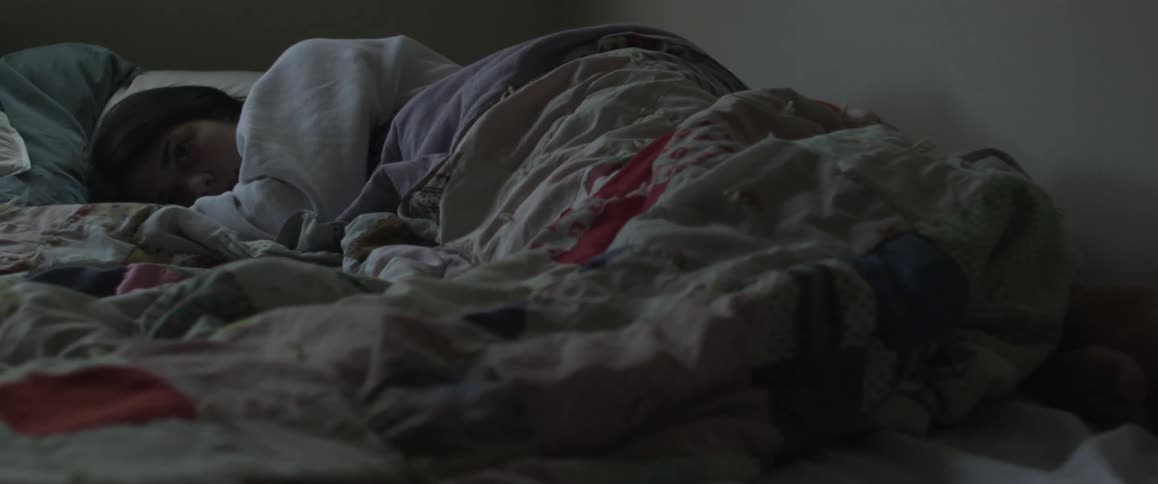 A woman is lying awake in a bed