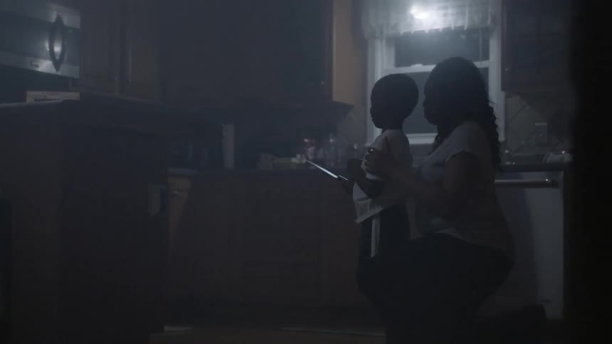 A young boy is consoled by his mother in the kitchen