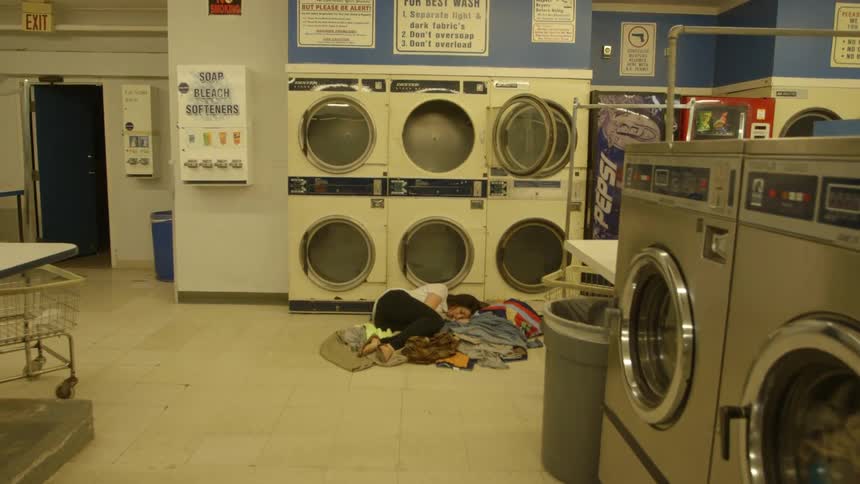 A woman is lying on the ground of the laundromat