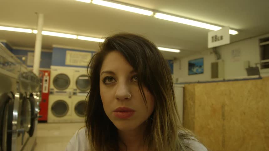 A woman goes around inside a laundromat