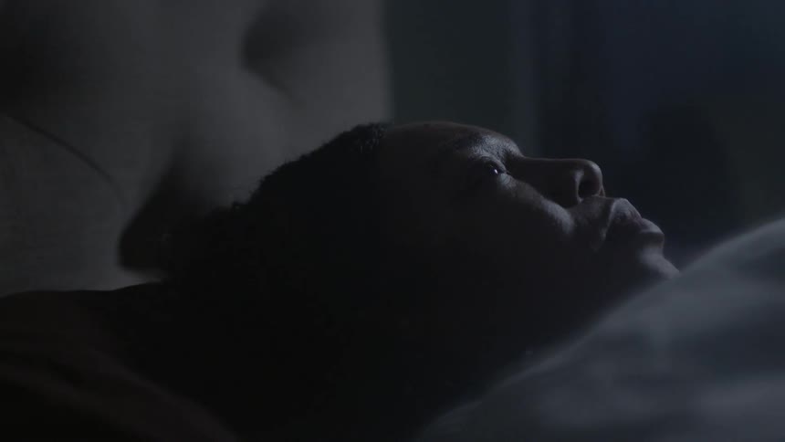 A woman is awoken while laying in bed