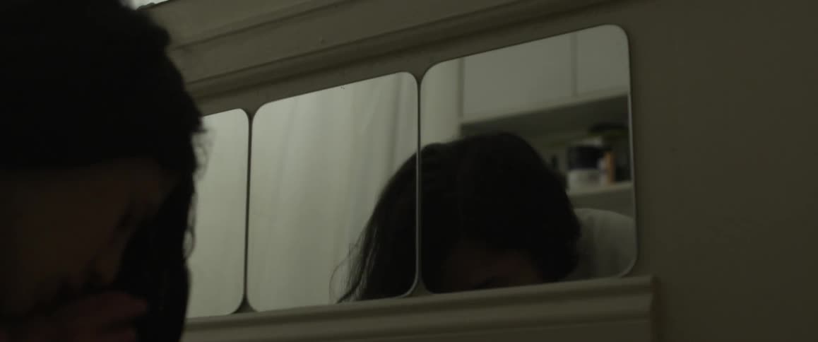 A woman washes her face in a bathroom