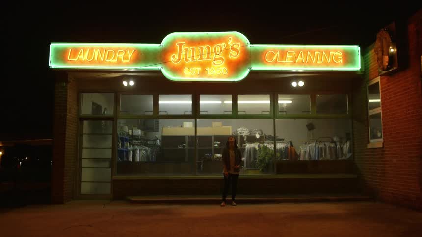 A woman stands outside a laundromat at night