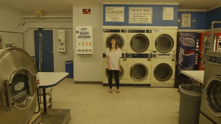 Woman in laundromat stares at the ceiling