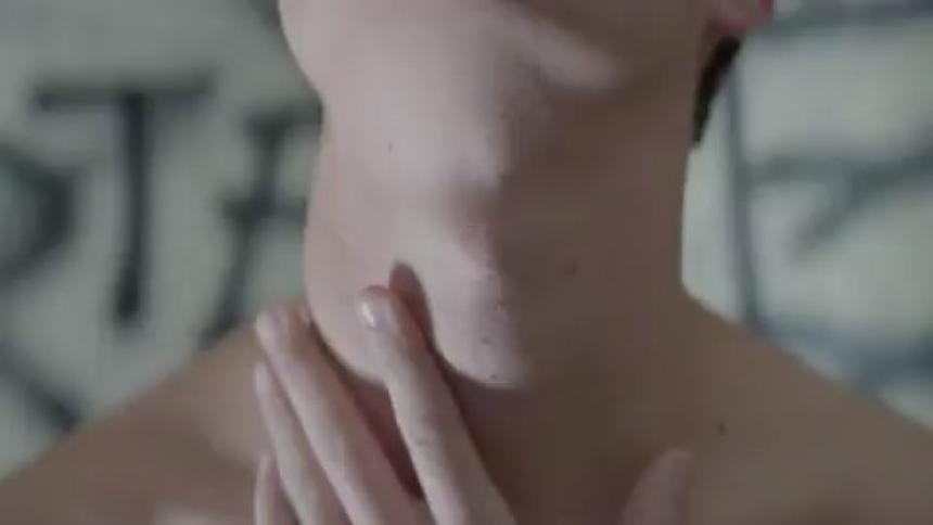 A young man is rubbing his neck in a room with a flashing light