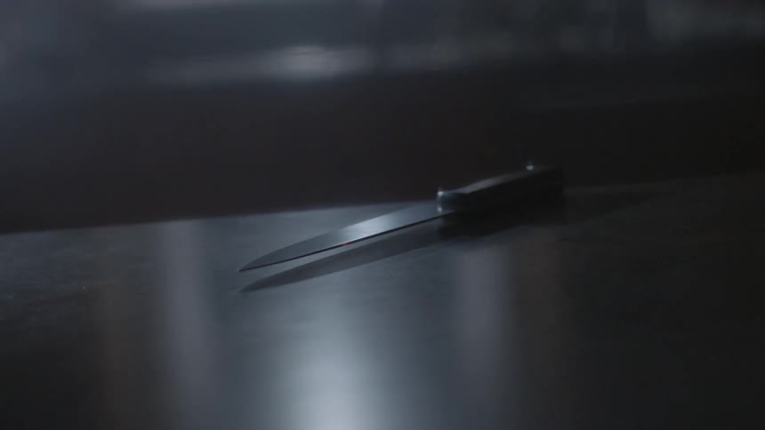 A knife is sitting on the table in a dark room