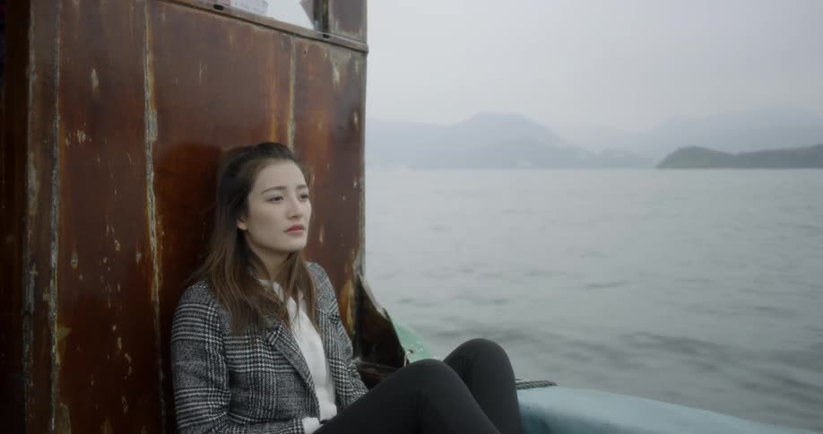 A woman is sitting on a boat as it travels through a large lake