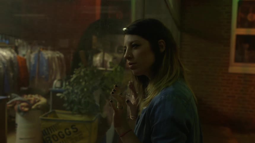 A woman leans against a store window