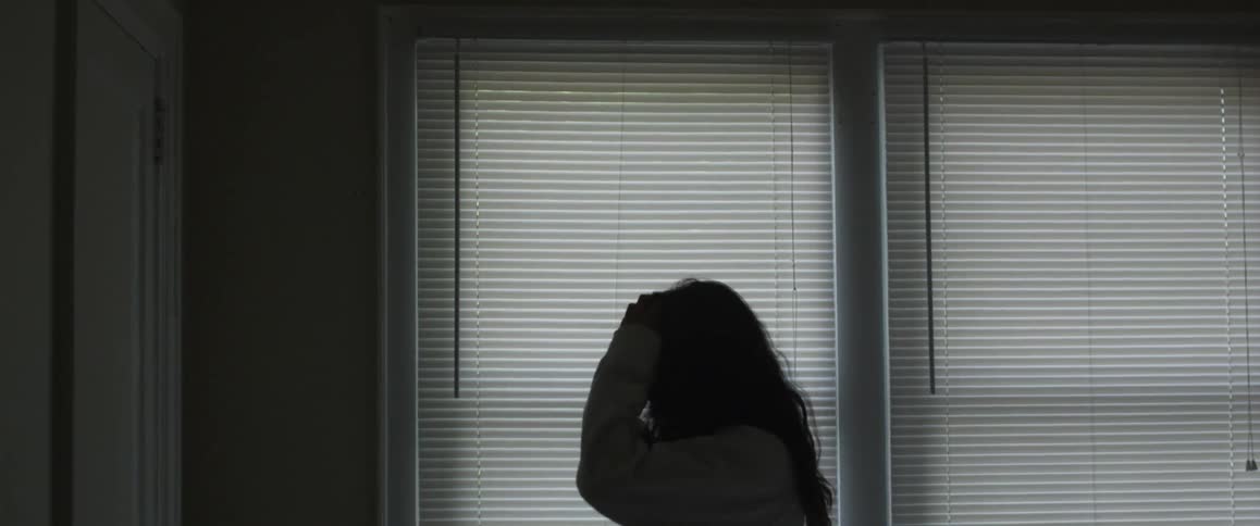 A woman peeks outside a window