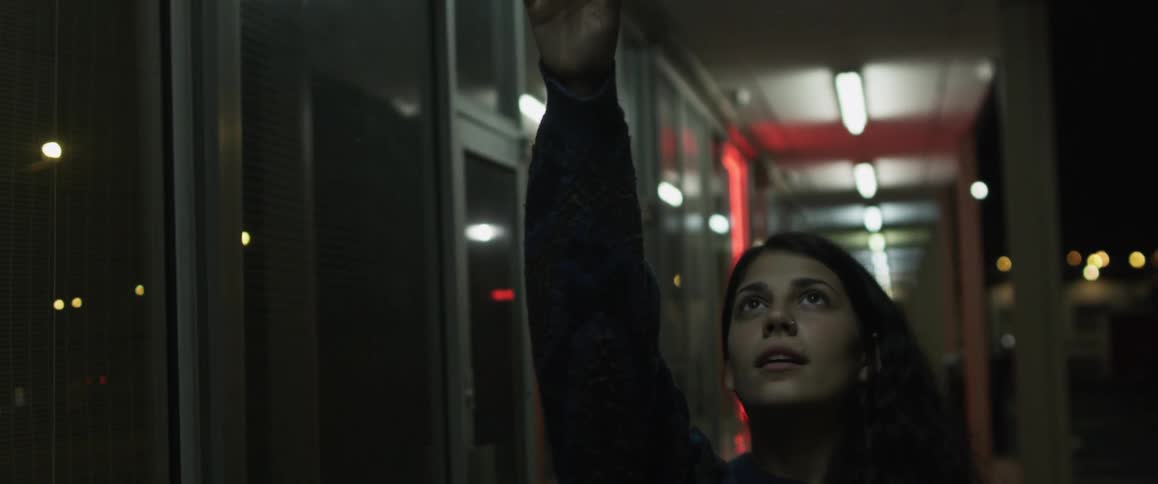 A woman reaches toward lights above her