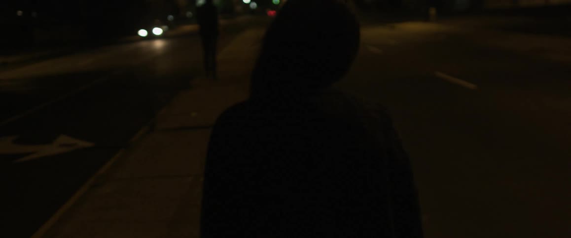 A woman is walking down the street with cars passing her by