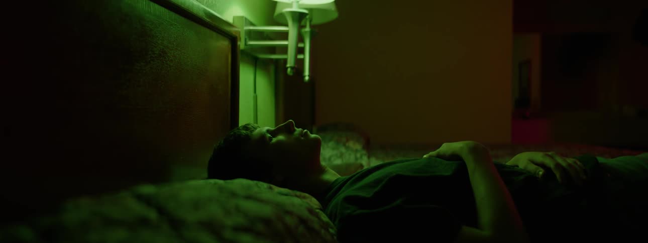 Man turns his head as he lays on a bed
