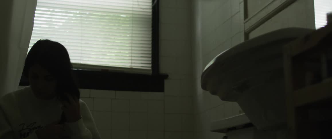 A woman is twisting her hair in a bathroom
