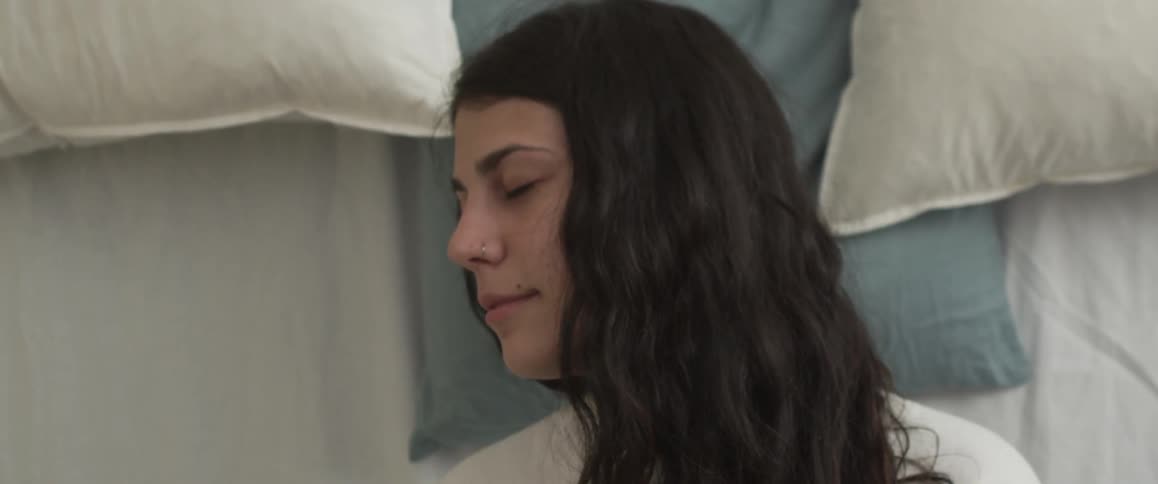Woman laying down on a bed with her eyes closed