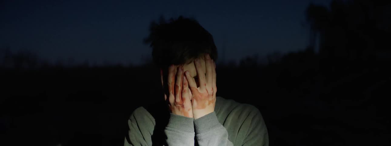 A light flashes on a teenager as he removes a mask and rubs his face
