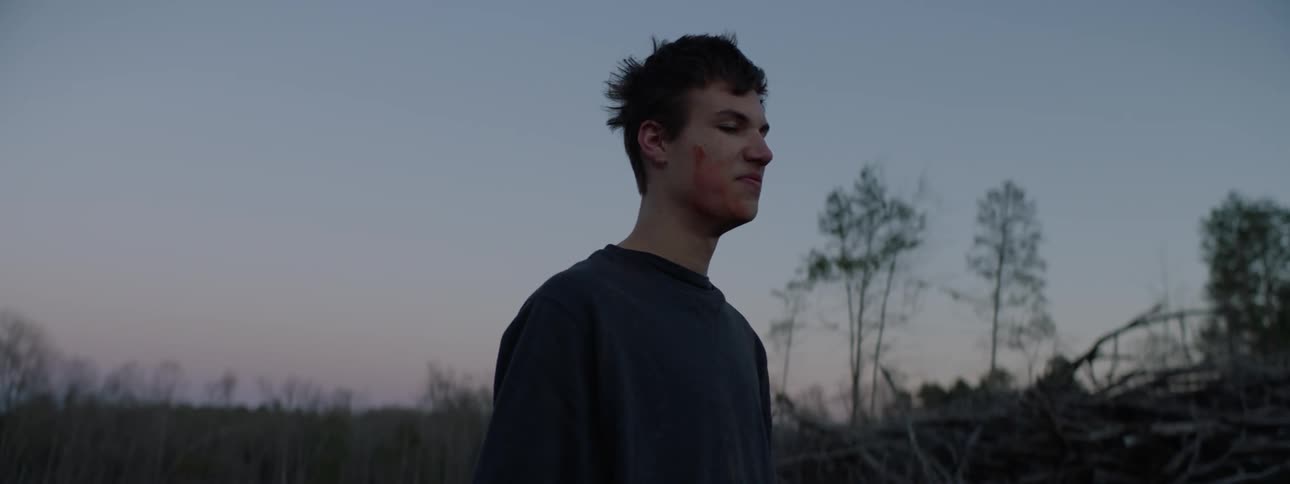 A man in a ski mask takes to mask off and has blood on his face