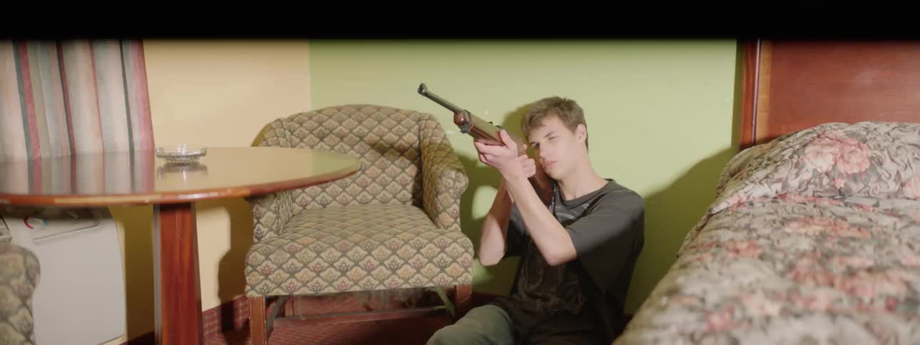 A young man grabbed a rifle from a table and is pointing it at something