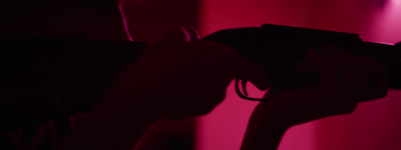 A young man is pointing a rifle at a mirror and pretending to fire it