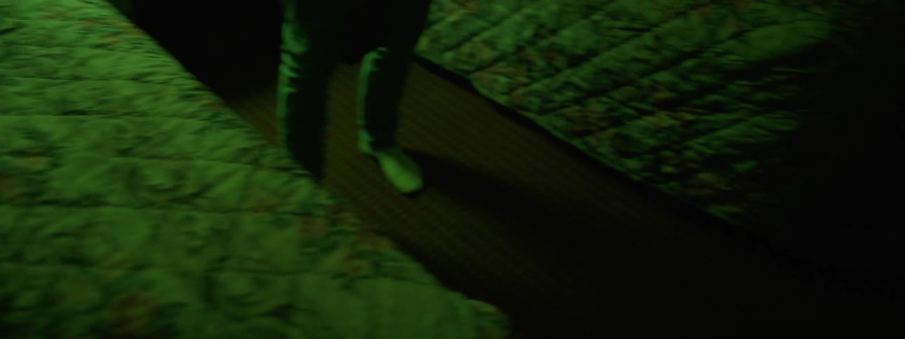A person picks a rifle up from the bed