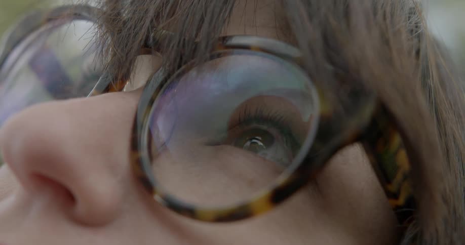 A woman wearing glasses looks upward