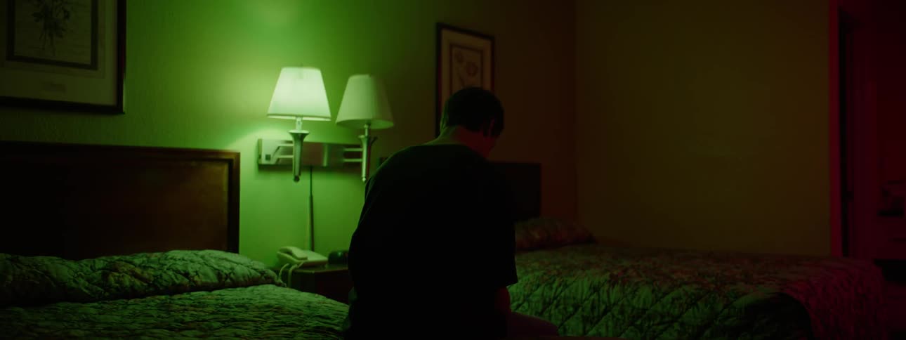 A man sits on a bed in a hotel