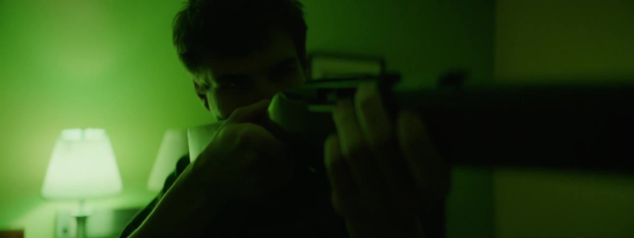A young man aims with a rifle