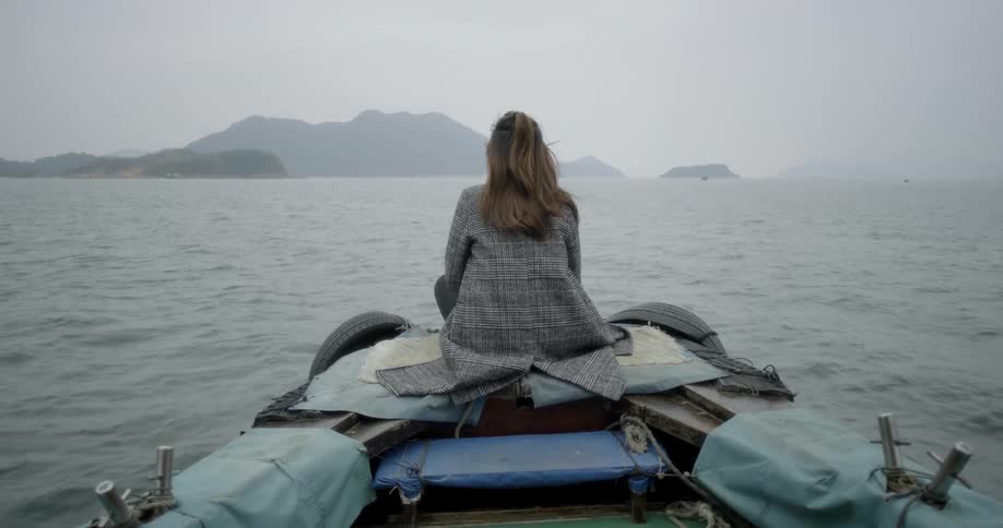 Woman sits on the edge of a boat in water
