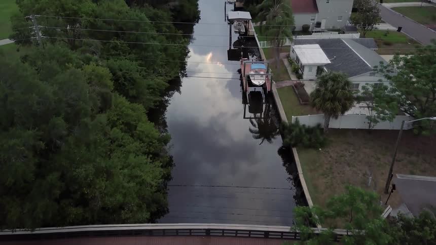 A small river with a bridge is being filmed from a drone