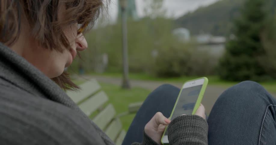 Woman sitting outside typing on a phone