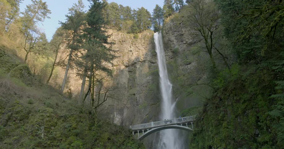 People on a bridge look at a waterfall