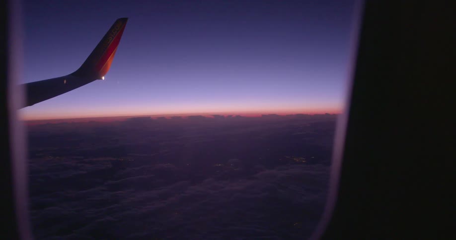 View looking out of an airplane window as day transitions to night