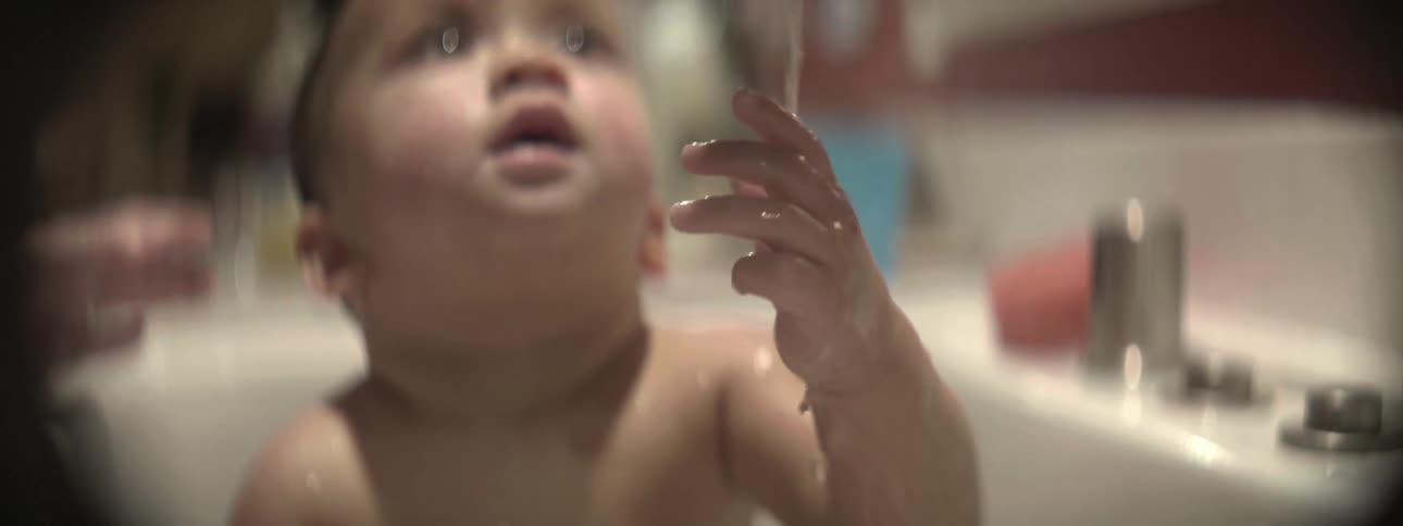 A baby takes a bath in a sink