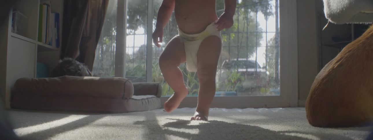 A toddler in a diaper wanders around