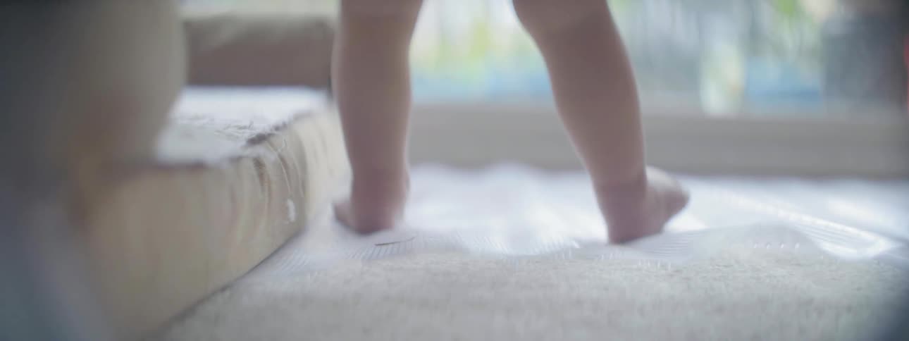 A baby is walking through the living room