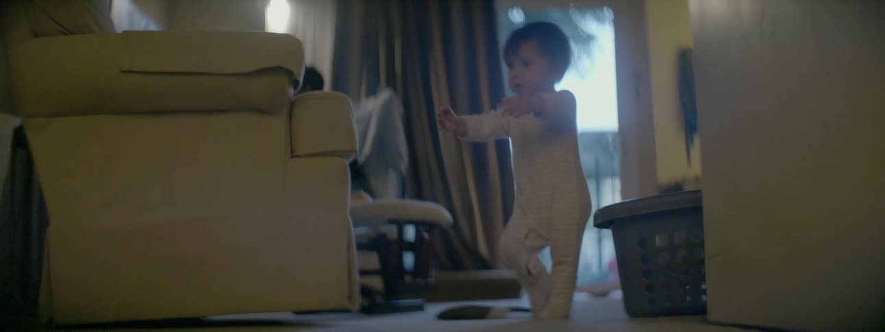 A dark-haired toddler walking around the living room