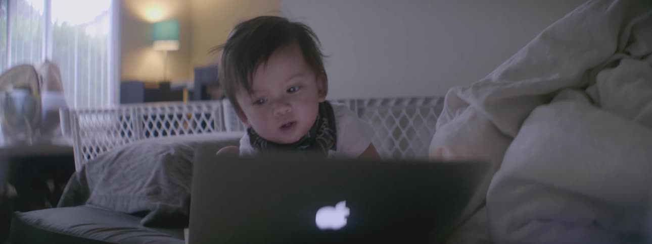 A toddler boy is playing with a macintosh laptop computer