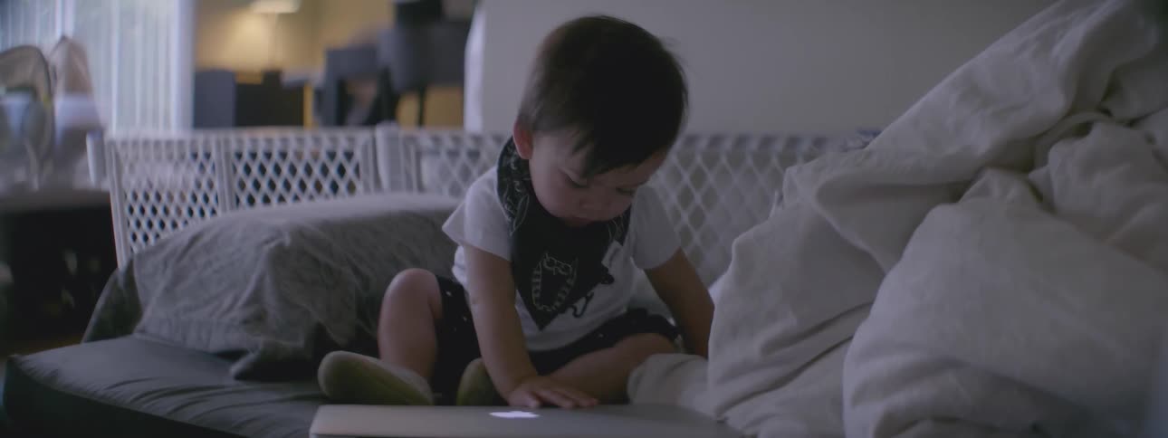A toddler is opening and closing a laptop
