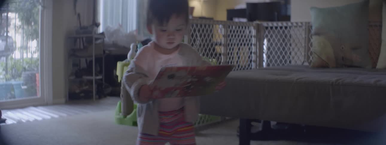 A baby walks around with a book