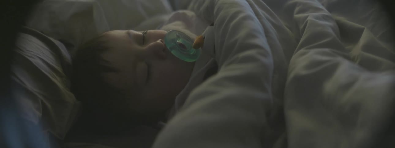 A baby sleeps under a blanket