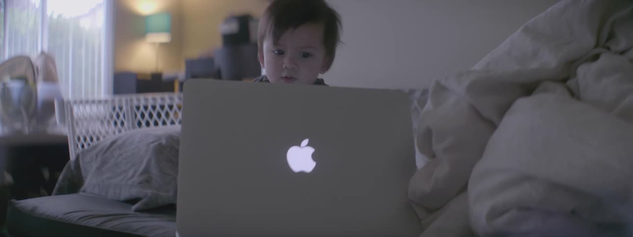 A young child opens up an apple laptop