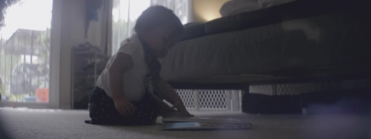 A baby opens a book on the floor