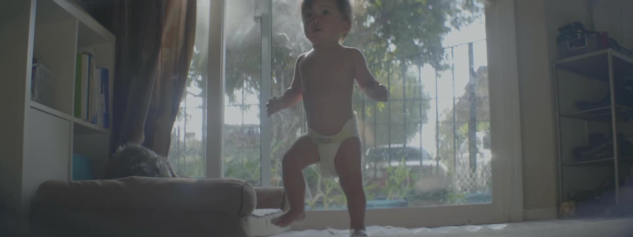 A baby walks past the window in the living room